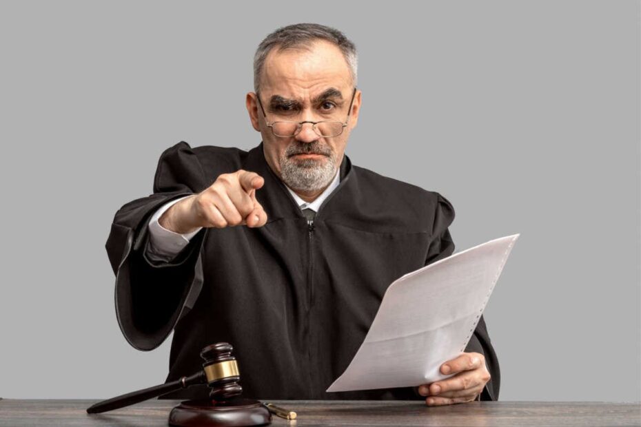 Richter mit Richterhammer mahnt mit ausgestrecktem Zeigefinger