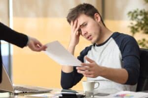 Chef überreicht frustriertem Arbeitnehmer ein Dokument, Symbolbild für Aufhebungsvertrag