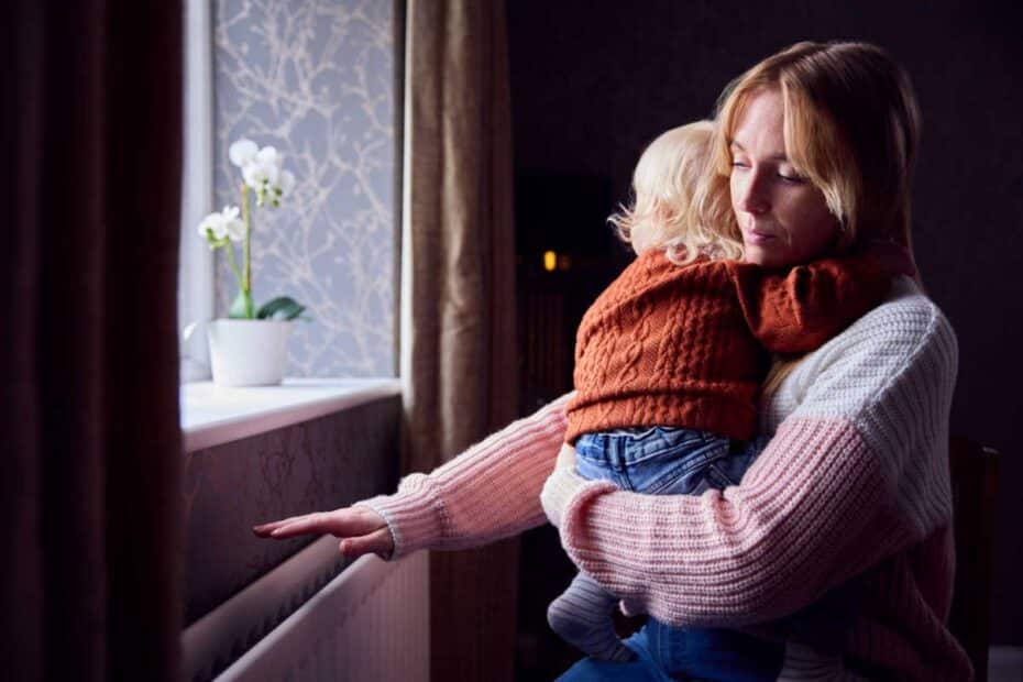 Junge Mutter mit Kind fühlt nach der Heizung