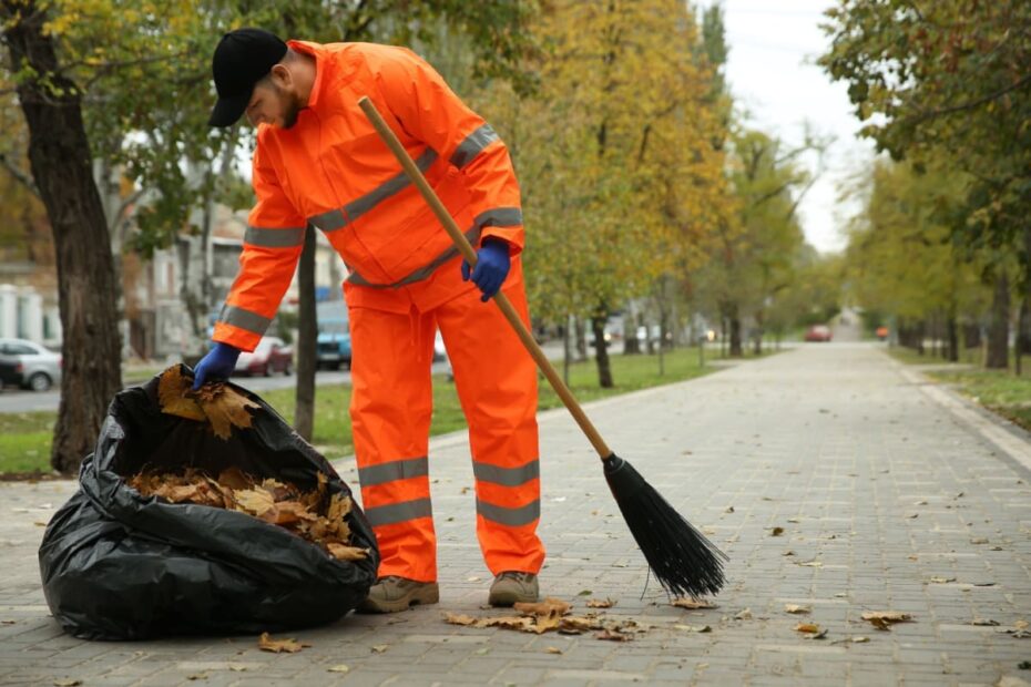 Mann fegt Straße und sammelt im Müllsack