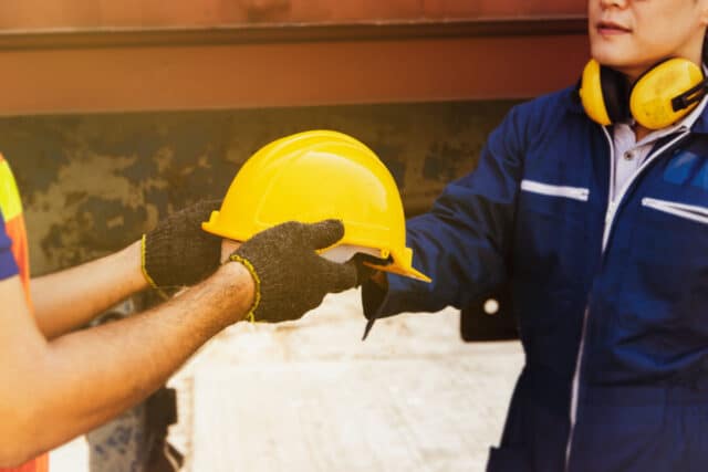 Industrieanlage mit 2 Mitarbeitern und gelbem Bauhelm