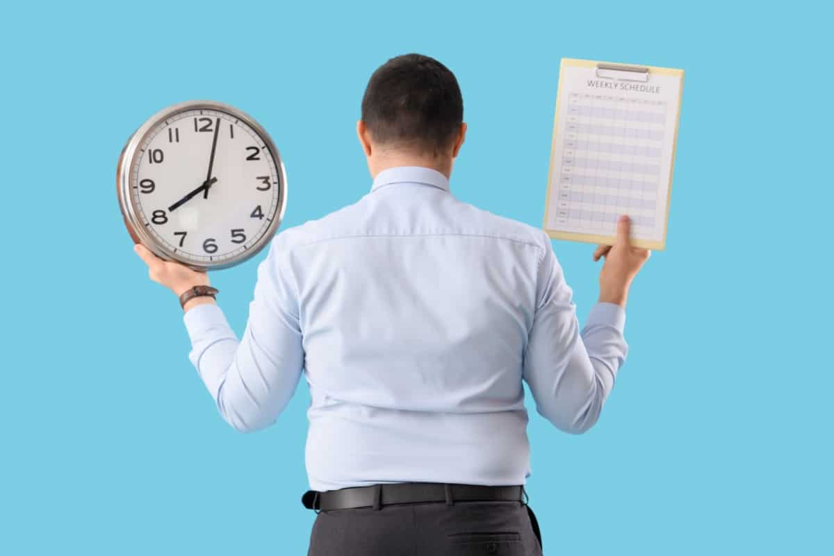 Symbolbild zum Thema Arbeitszeitbetrug: Ein Mann hält eine Uhr und einen Arbeitsplan, was die strikte Trennung von Arbeitszeit und Privatzeit verdeutlicht.