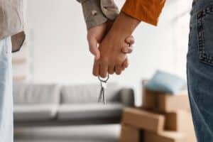 Mann und Frau halten gemeinsam Schlüssel für neue Wohnung in der Hand