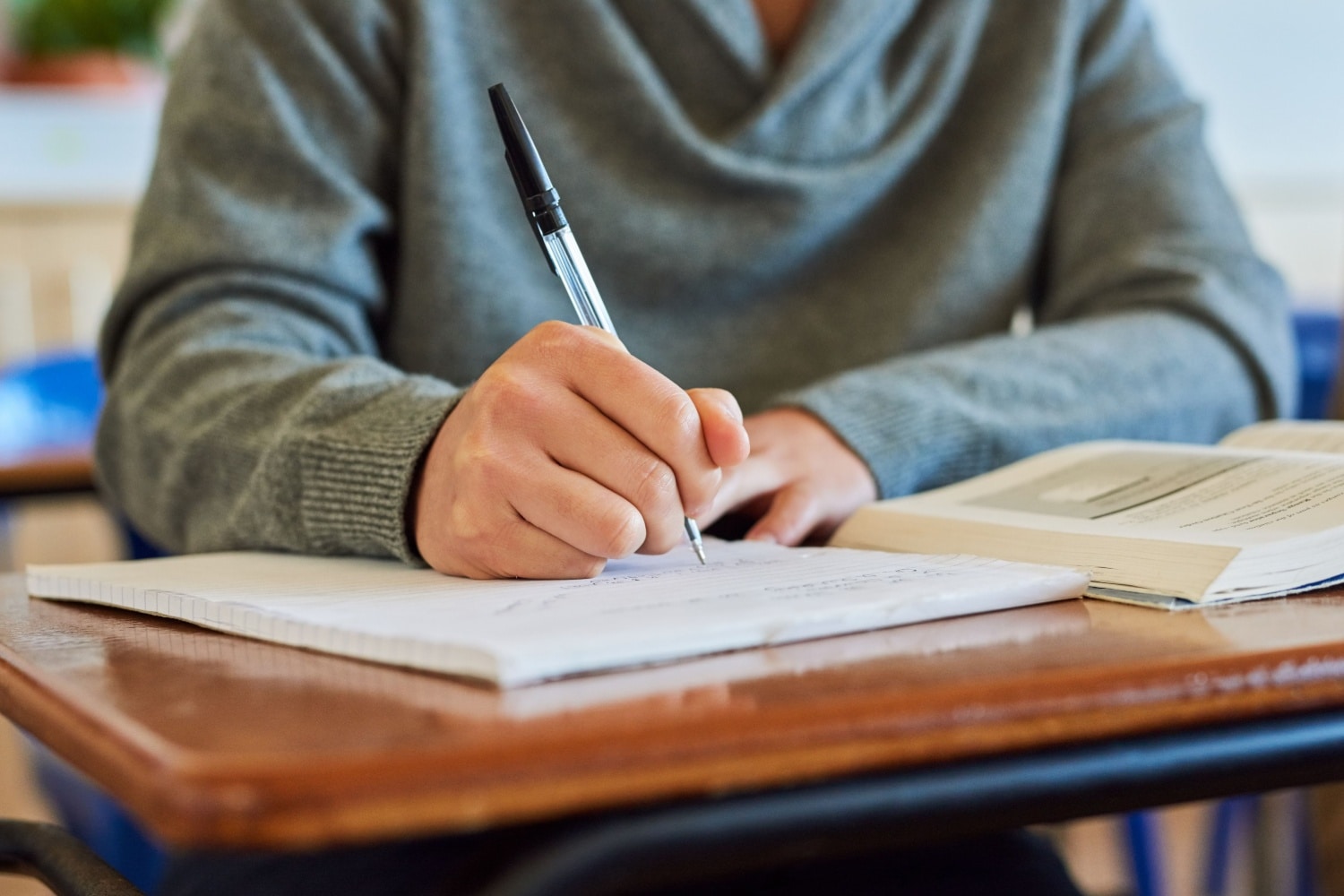 Schülerin schreibt im Klassenzimmer in ein Heft – Symbolbild für Bildung und Schulabschluss als Schlüssel zur Dauer des Bürgergeld‑Bezugs