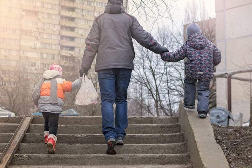 Vater geht mit Kindern Treppe hoch