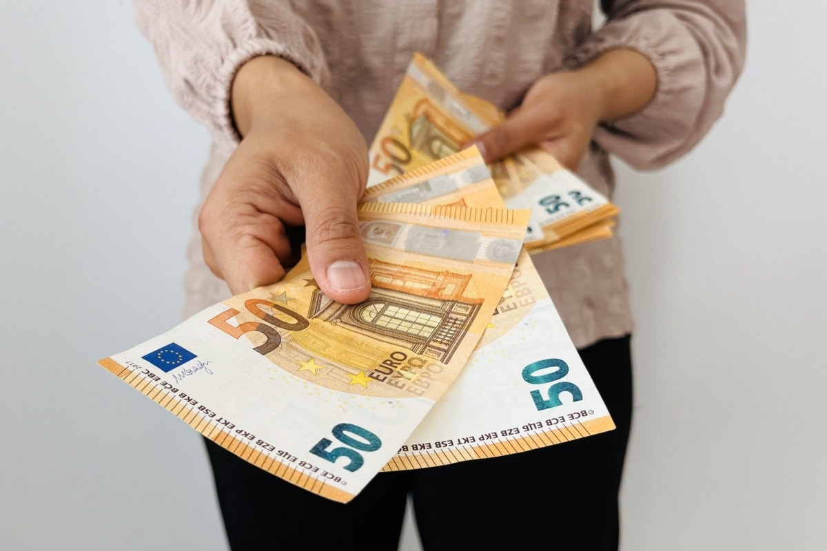 Frau reicht einige 50 Euro Scheine, symbolisch für Geldgheschenk