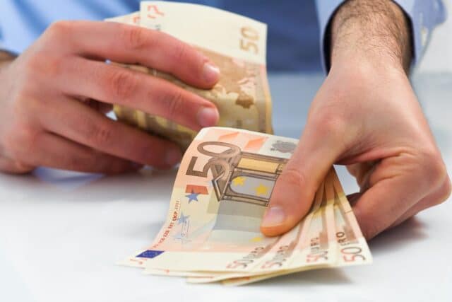 Mann zählt 50-Euro-Scheine – Symbolbild für Bürgergeld-Nachzahlung und Rückforderung