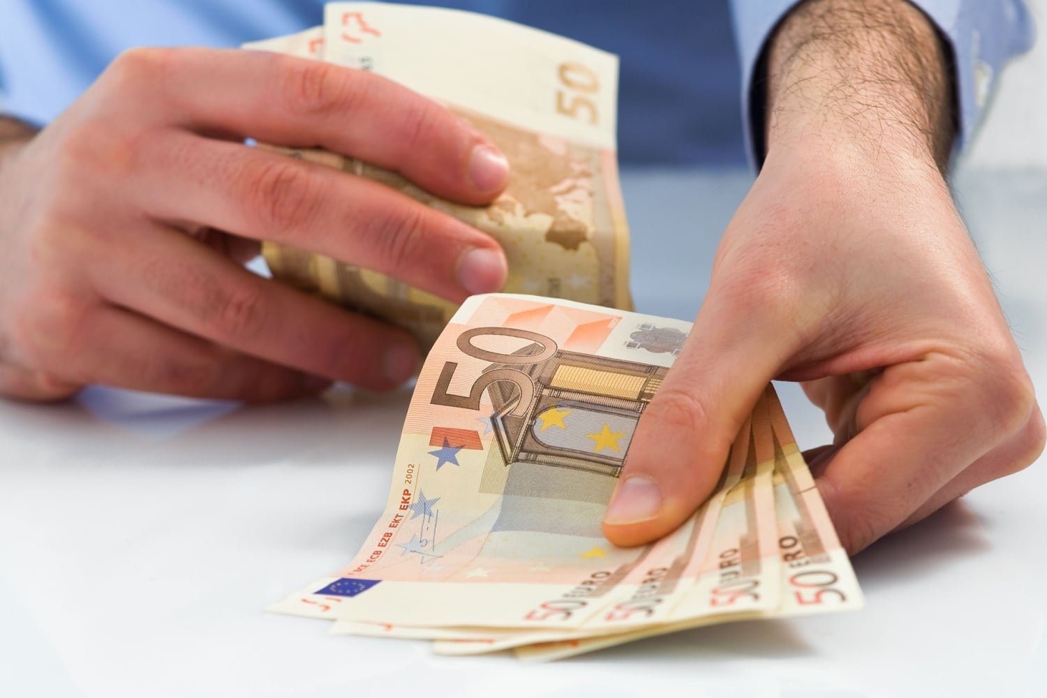 Mann zählt 50-Euro-Scheine – Symbolbild für Bürgergeld-Nachzahlung und Rückforderung
