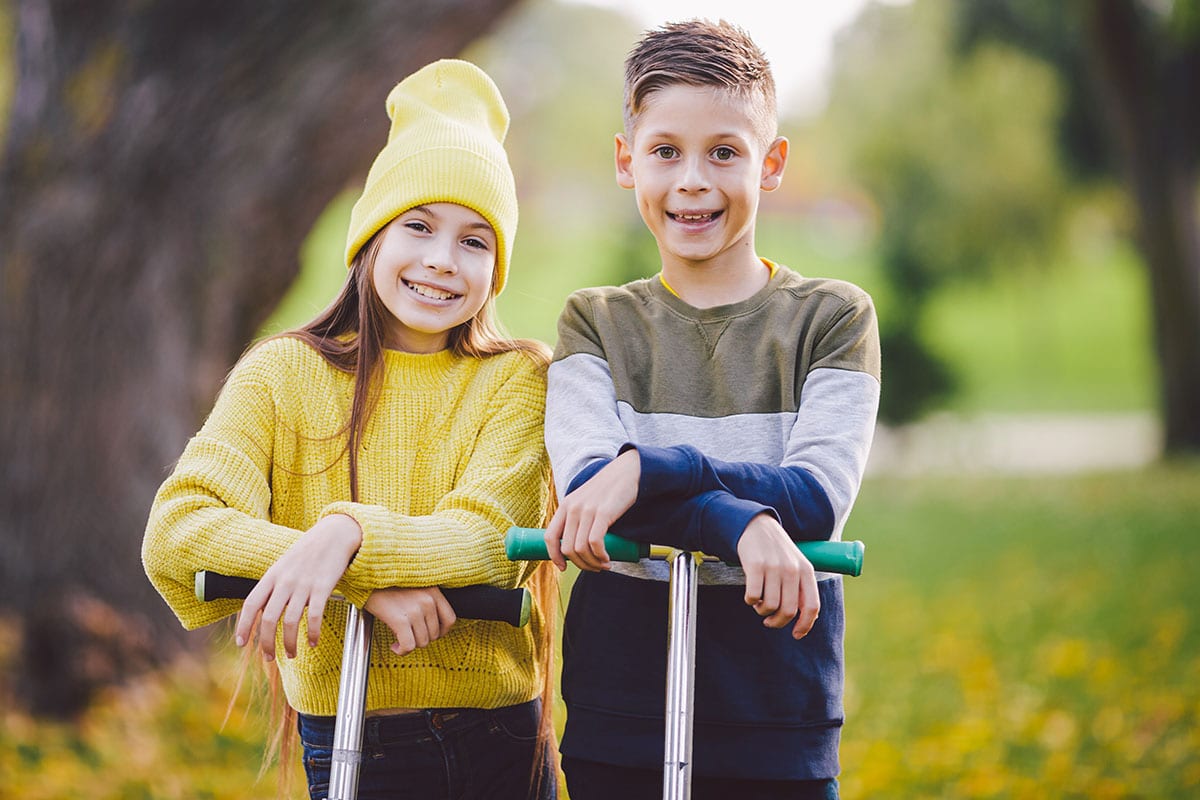 Zwei Kinder mit Roller im Park