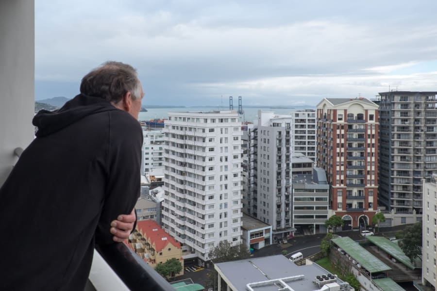 Mann schaut nachdenklich vom Balkon eines Hochhauses