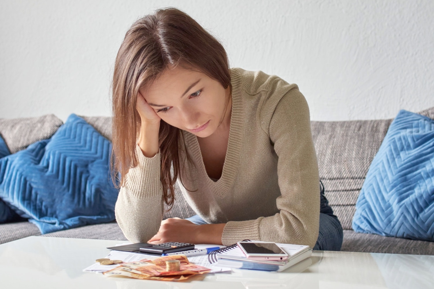 Junge Studentin sitzt am Tisch und prüft ihre Finanzen