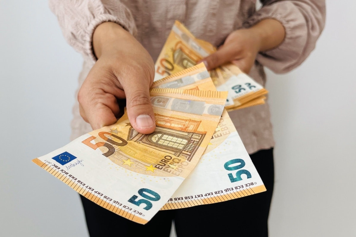 Frau gibt einer anderen Person Geldscheine – Symbolbild für private Spende und Bürgergeld