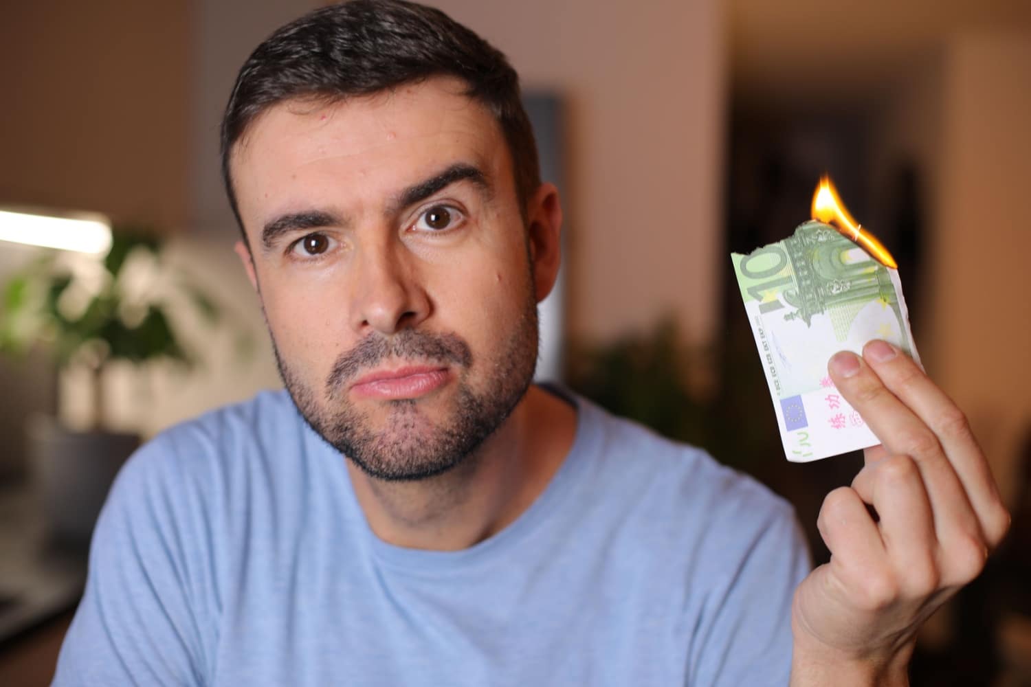 Mann hält brennenden 100 Euro Geldschein hoch - symbolisch für nicht lohnende Arbeit
