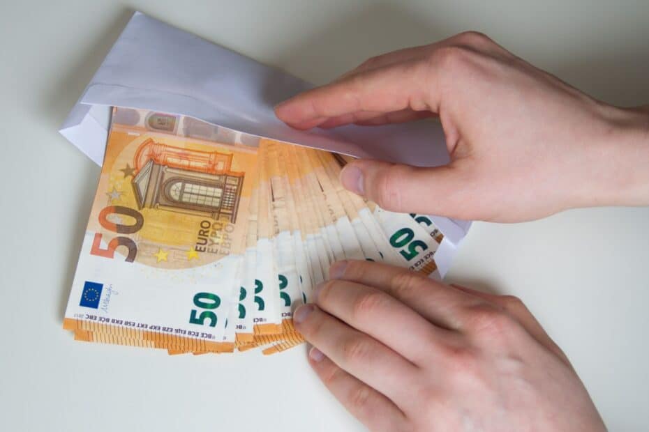 Hände stecken Bargeld in einen Umschlag