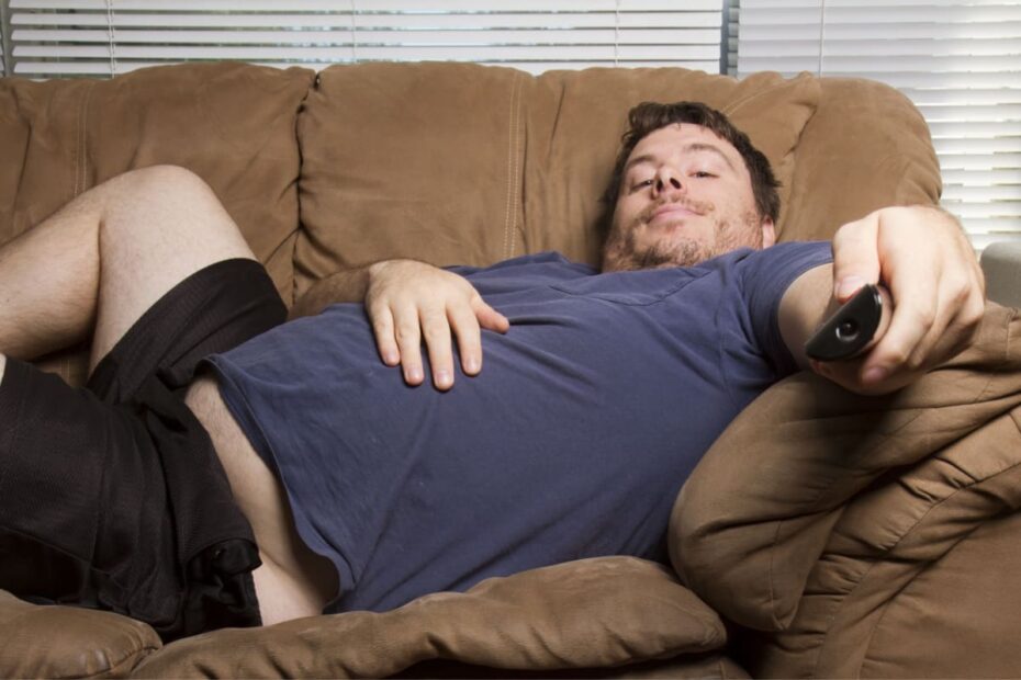 Fauler übergewichtiger Mann auf Sofa mit Fernbedienung
