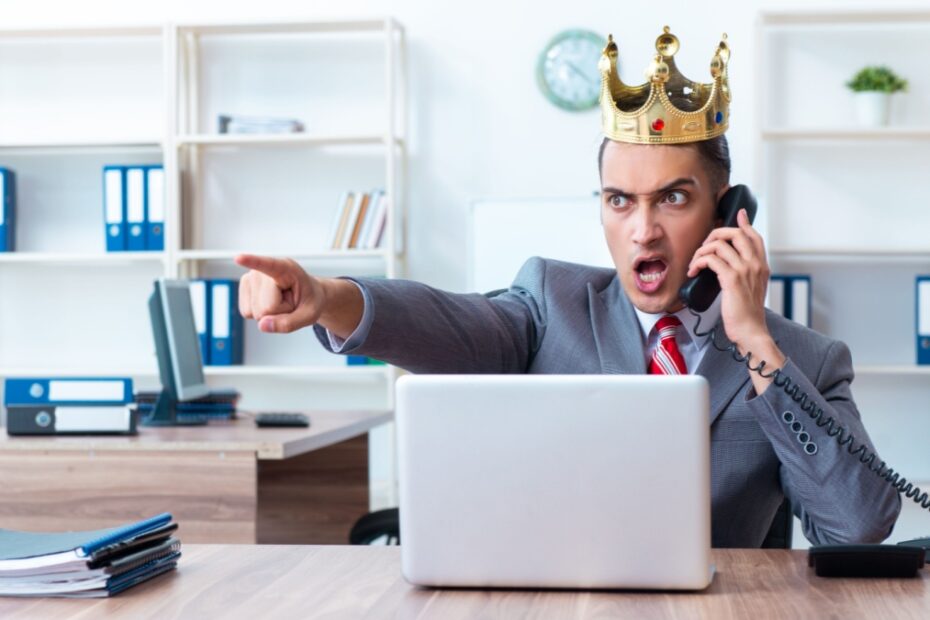 Satirische Darstellung eines wütenden, autoritären Jobcenter-Mitarbeiters (Sachbearbeiter) mit goldener Königskrone, der schreiend telefoniert und mit dem Finger Befehle erteilt.