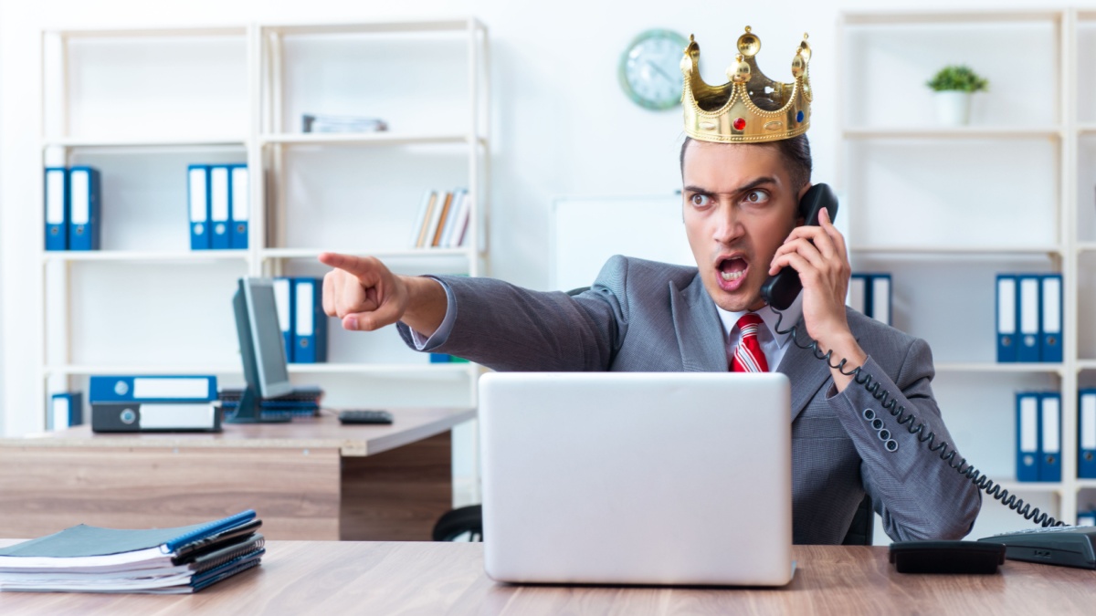 Satirische Darstellung eines wütenden, autoritären Jobcenter-Mitarbeiters (Sachbearbeiter) mit goldener Königskrone, der schreiend telefoniert und mit dem Finger Befehle erteilt.