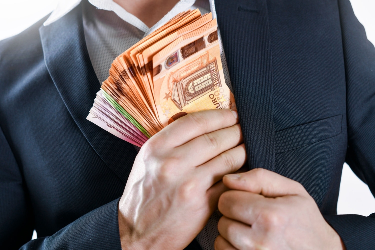 Mann versteckt heimlich Bündel von Euro-Scheinen in seinem Sakko, Symbol für Bürgergeld-Betrug