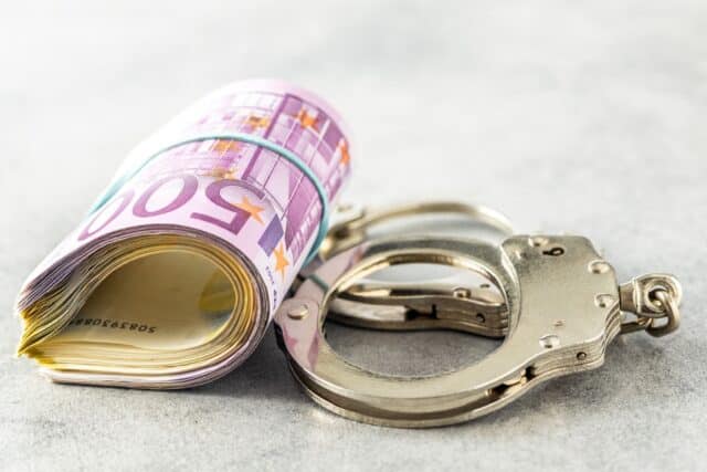Euro-Geldbündel neben Handschellen, symbolisch für Bürgergeld Betrug