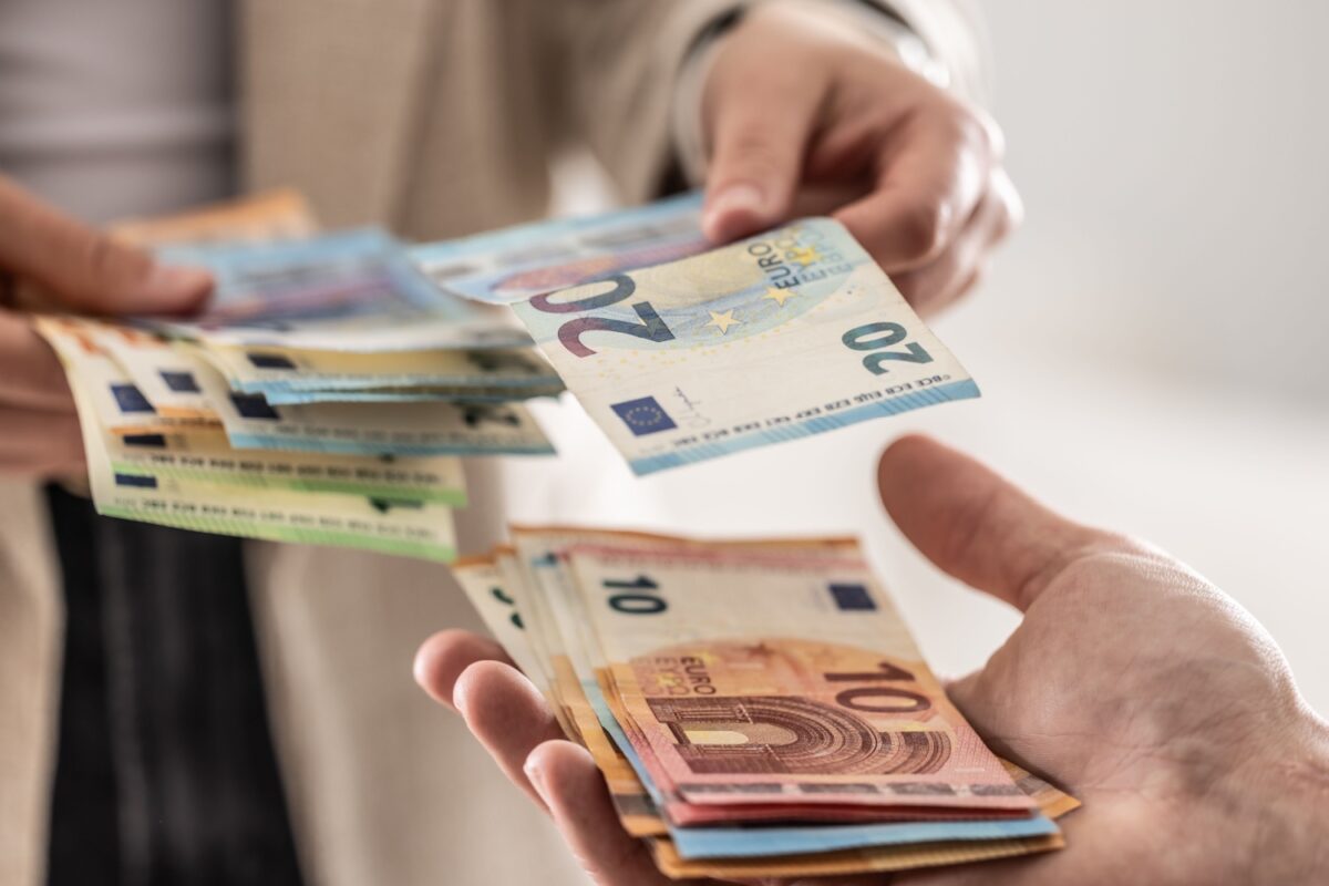 Geldübergabe mit Euro-Scheinen – Symbolbild für organisierten Bürgergeld-Betrug