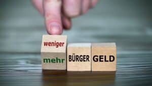 Holzwürfel mit Aufschrift Bürgergeld und mehr oder weniger