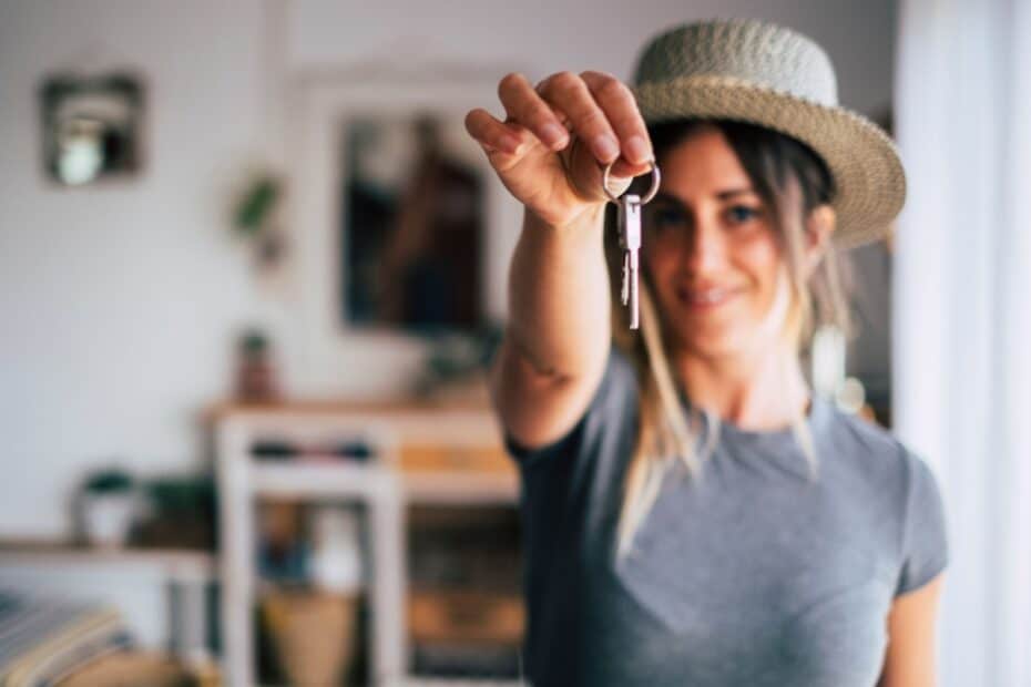 Eine junge Frau lächelt und hält den Schlüssel für ihre erste eigene Wohnung in die Kamera – passend zum Thema Bürgergeld und Auszug unter 25 Jahren.