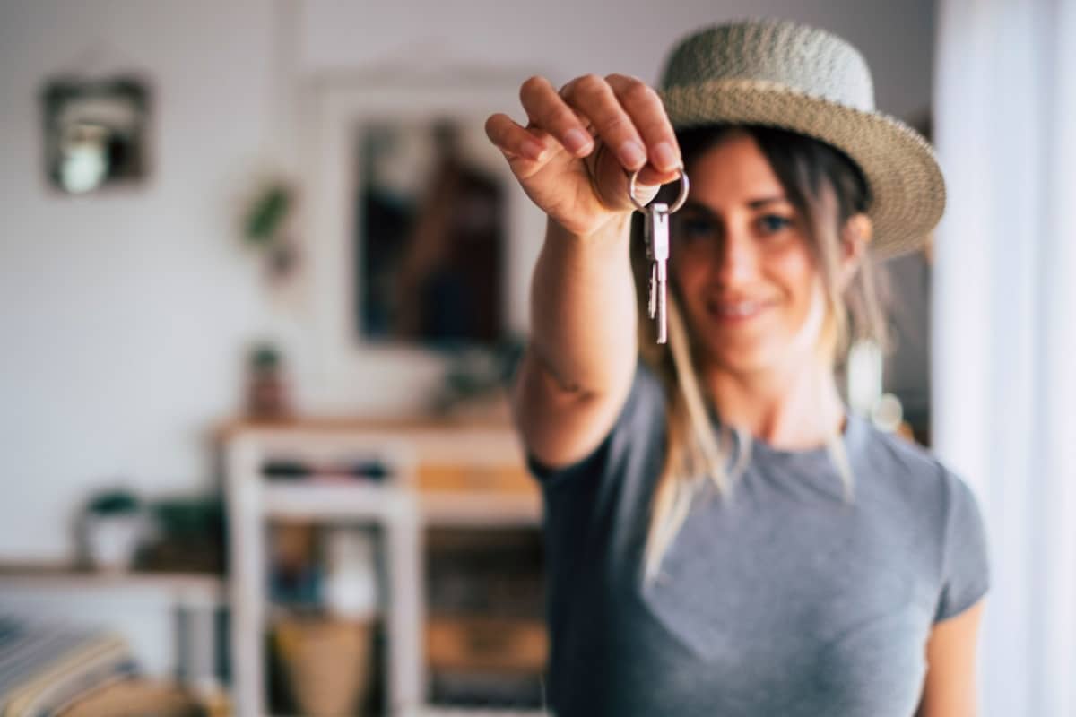 Eine junge Frau lächelt und hält den Schlüssel für ihre erste eigene Wohnung in die Kamera – passend zum Thema Bürgergeld und Auszug unter 25 Jahren.