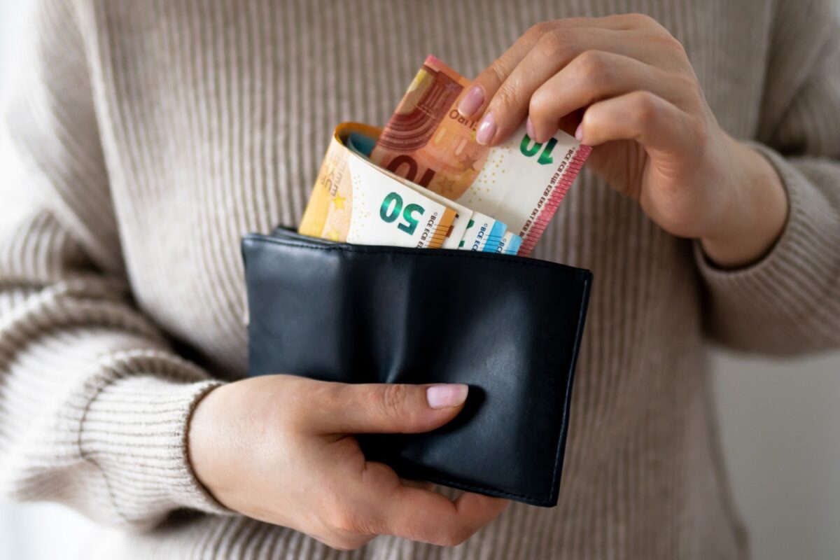Hände nehmen einige Geldscheine aus einer Geldbörse