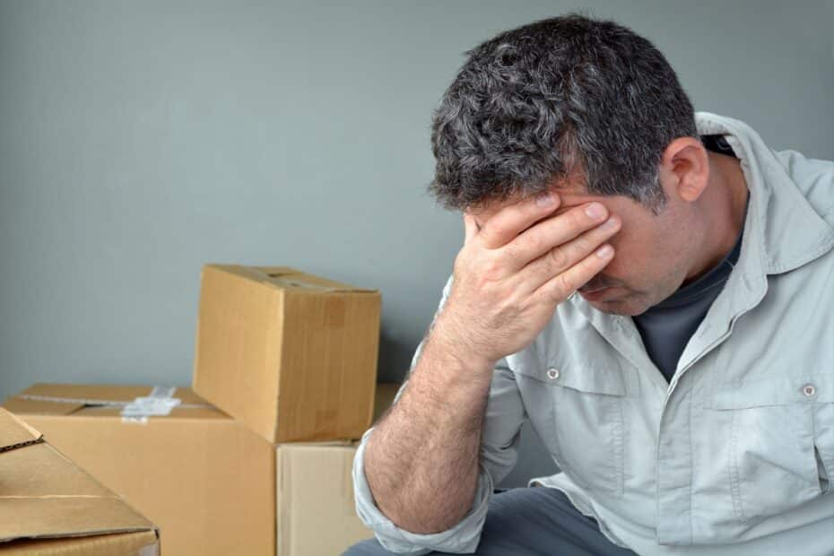 Verzweifelter, älterer Mann sitzt neben gepackten Umzugskartons
