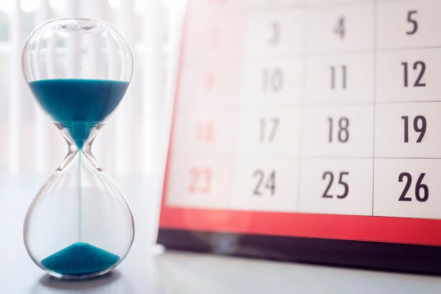 Sanduhr vor Kalender, symbolisch für Karenzzeit beim Bürgergeld für Vermögen und Miete