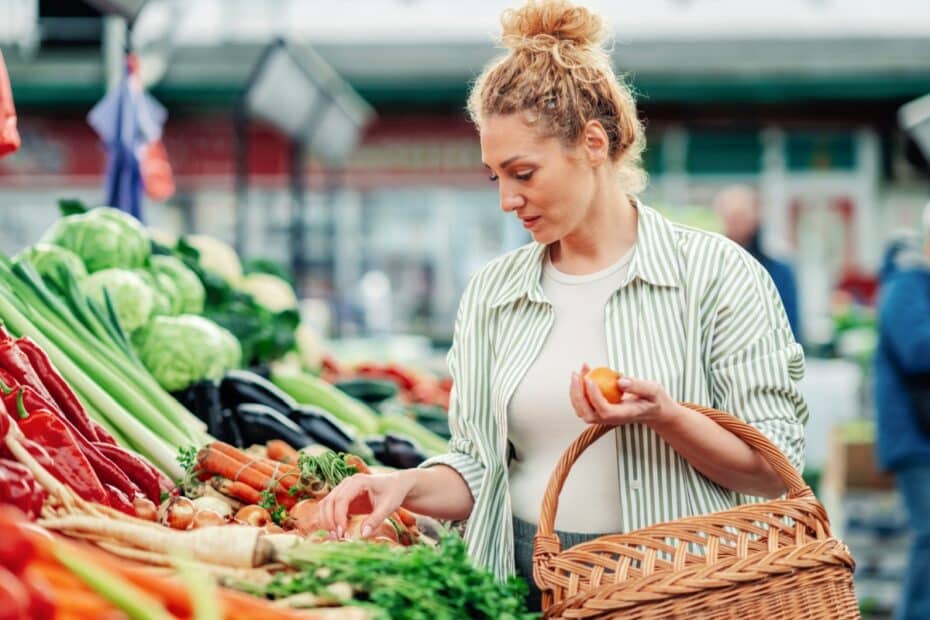 Frau steht im Supermarkt in der Gemüseabteilung