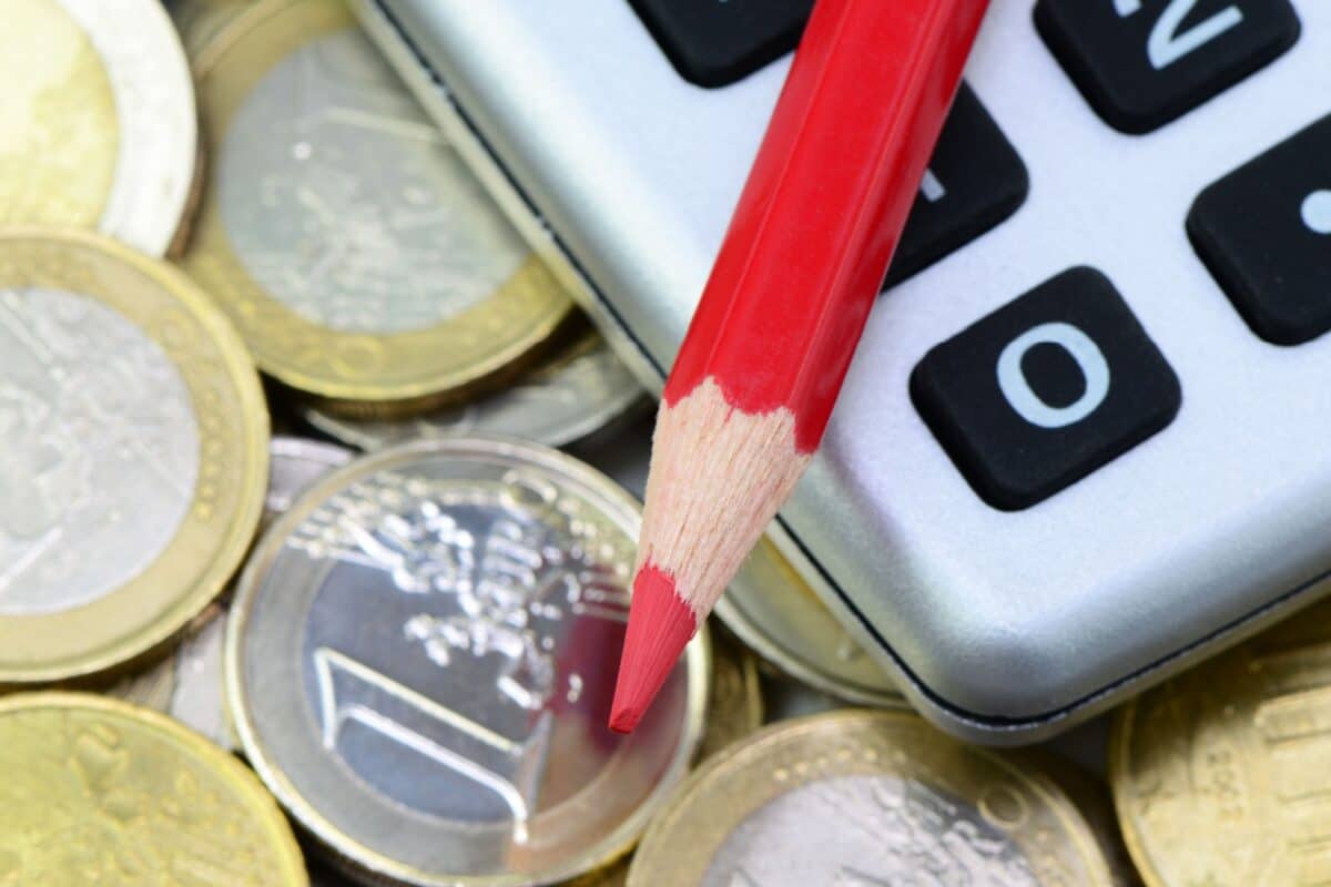Rotstift auf Taschenrechner mit Geldmünzen