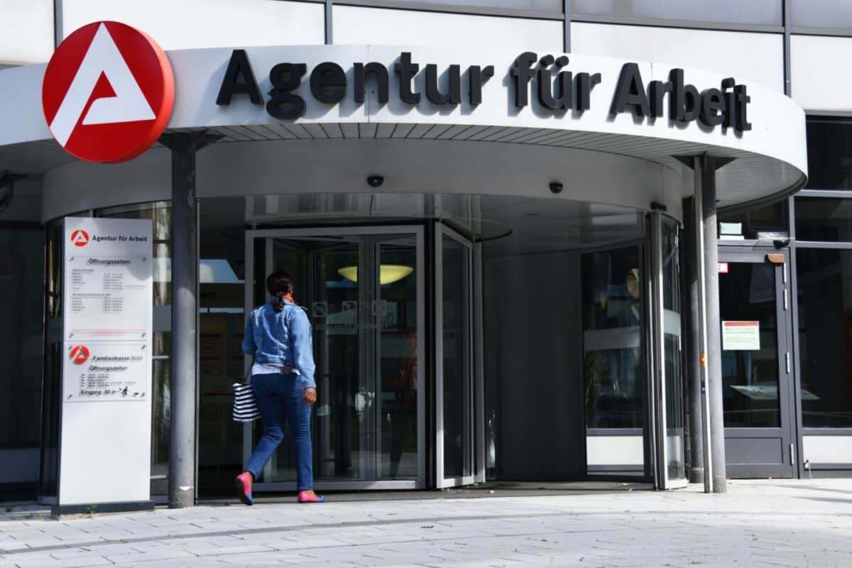 Frau betritt ein Jobcenter über die Drehtür am Haupteingang