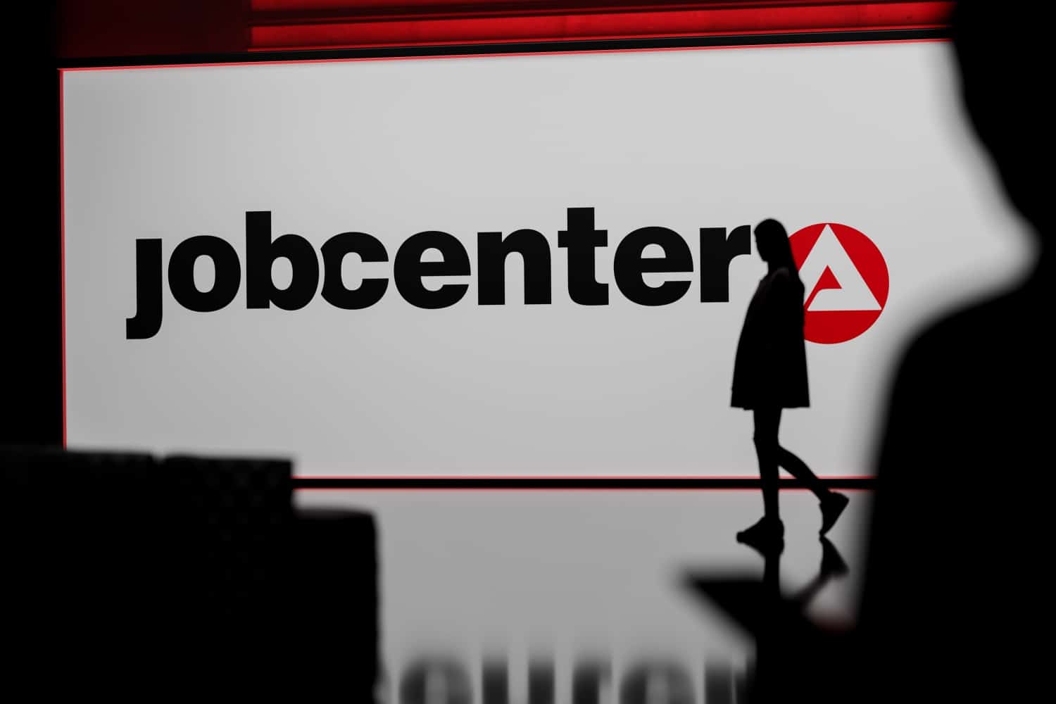Jobcenter im Hintergrund Logo und Silhouette einer Frau im Vordergrund