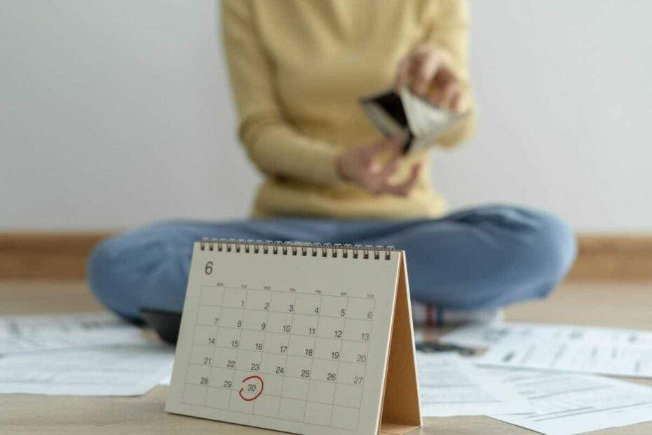 Frau mit leerem Portemonnaie und Kalender im Vordergrund