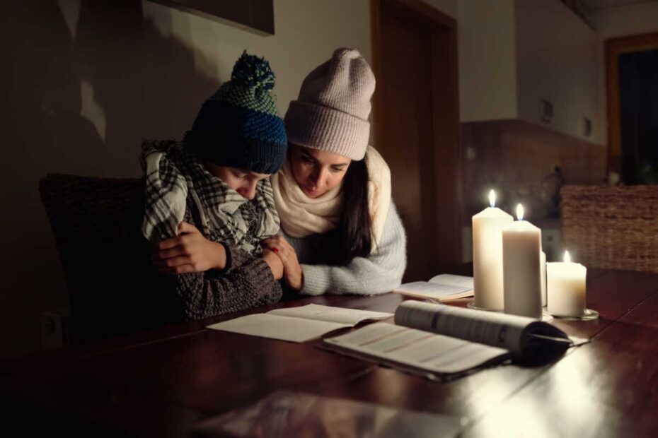 Mutter mit Kind sitzen im Dunkeln bei Kerzen weil Strom angeschaltet wurde