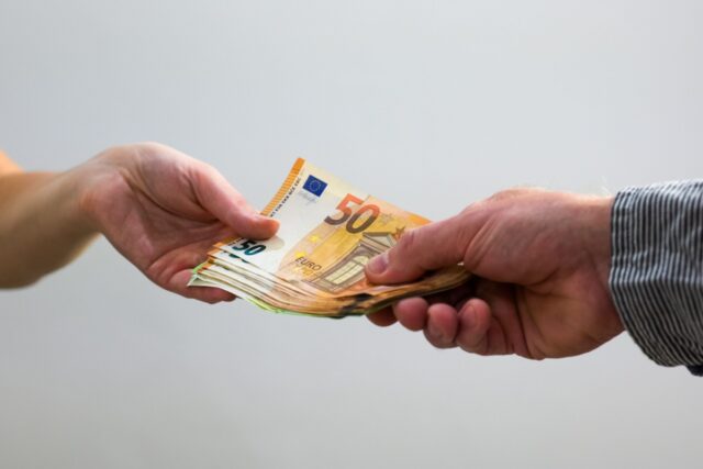 Nahaufnahme einer Barzahlung mit Euro-Geldscheinen als Symbol für Schwarzarbeit und nicht gemeldetes Einkommen.