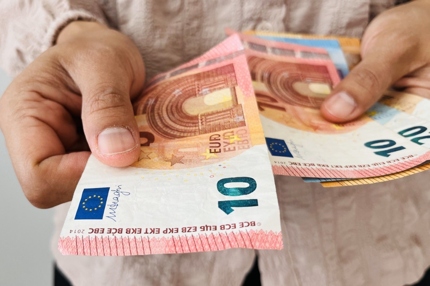 Hand hät mehrere 10 € Scheine hin, symbolisch für Taschengeld
