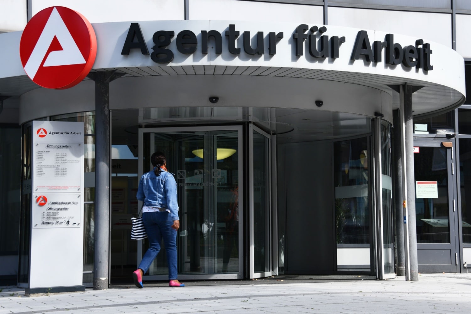 Frau betritt das Arbeitsamt über eine Drehtür