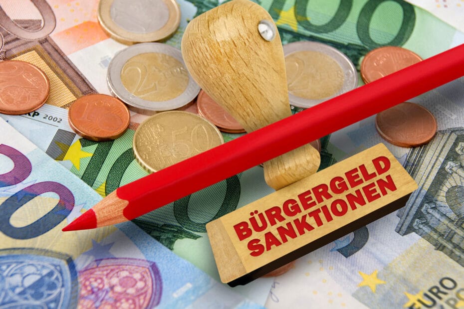 Euro Geldscheine und Münzen mit einem roten Buntstift und Stempel mit Aufschrift Bürgergeld Sanktionen