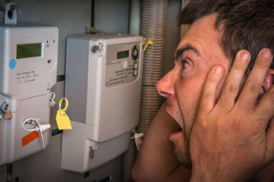 Mann steht entsetzt vor Stromzähler