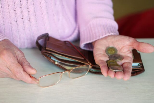 Arme Rentnerin mit Kleingeld in der Hand