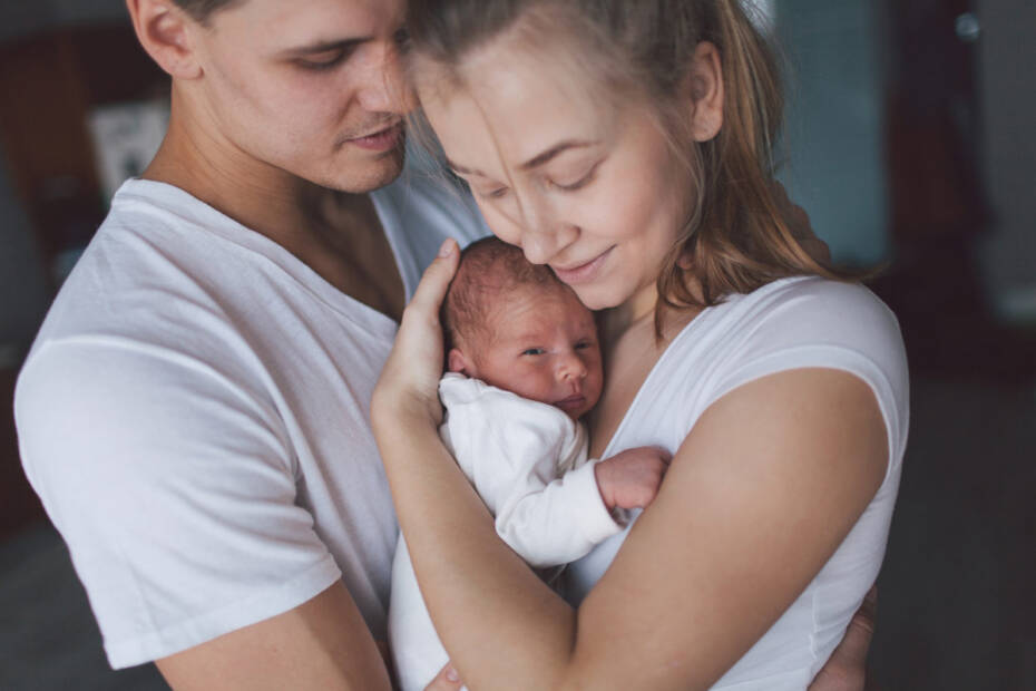 Mutter und Vater halten neugeborenes Baby im Arm