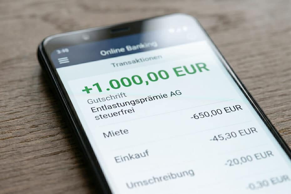Smartphone mit offener Banking App, auf der der Eingang von 1.000 Euro Entlastungsprämie zu sehen sind