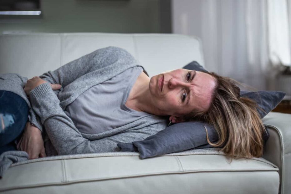 Frau liegt auf dem Sofa mit Bauschschmerzen