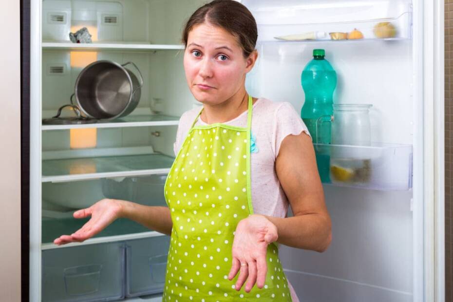 Junge Frau vor leerem Kühlschrank