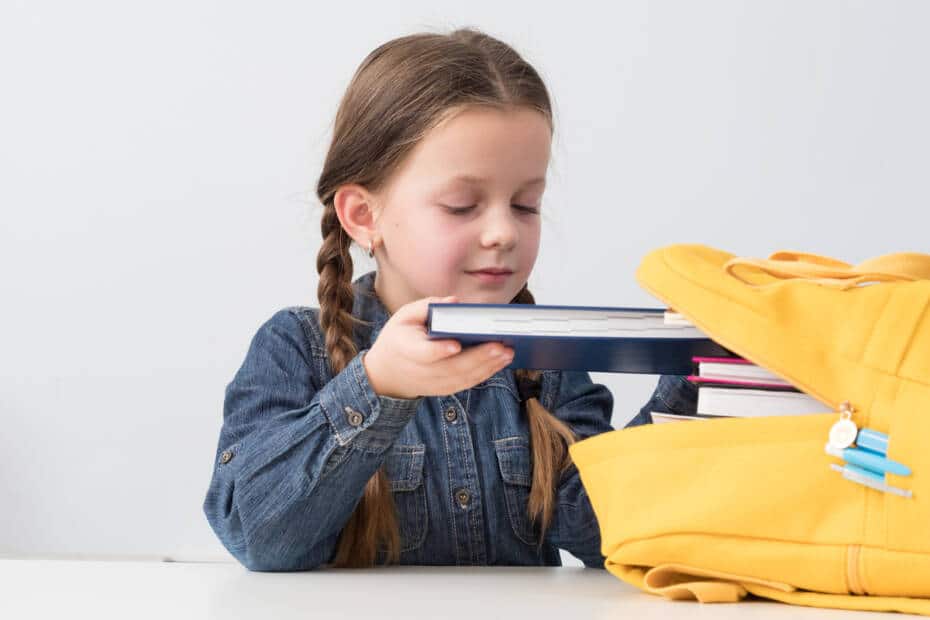 Kind steckt Schulbücher in den Rucksack