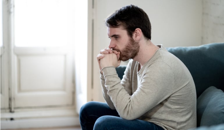 Trauriger Mann sitzt in seiner Wohnung