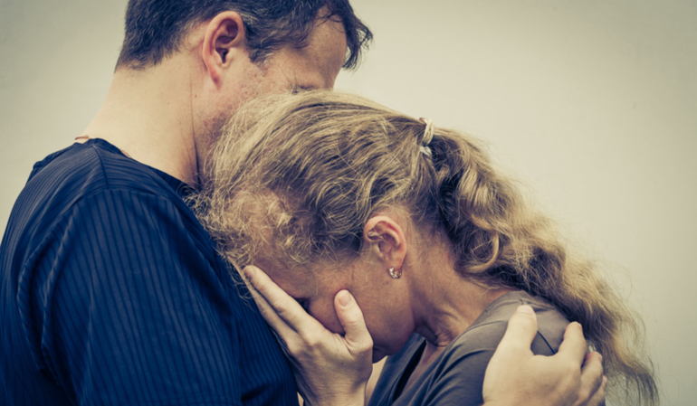 Trauriger Mann hält seine weinende Frau fest