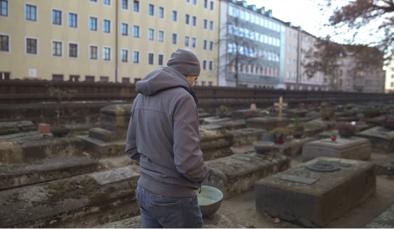 Ein Mann geht auf einem Friedhof entlang